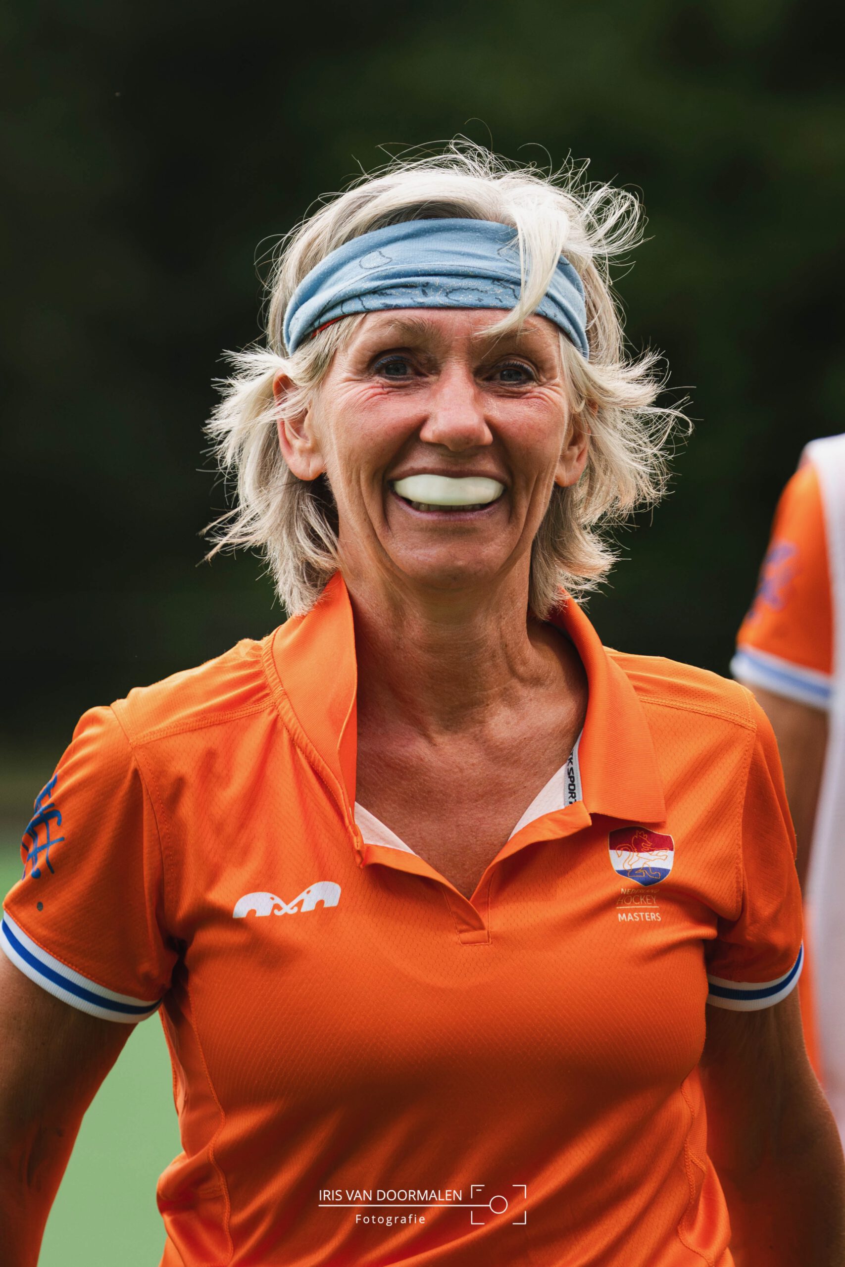 Nederlandse hockeyster in oranje kijkt lachend naar haar publiek