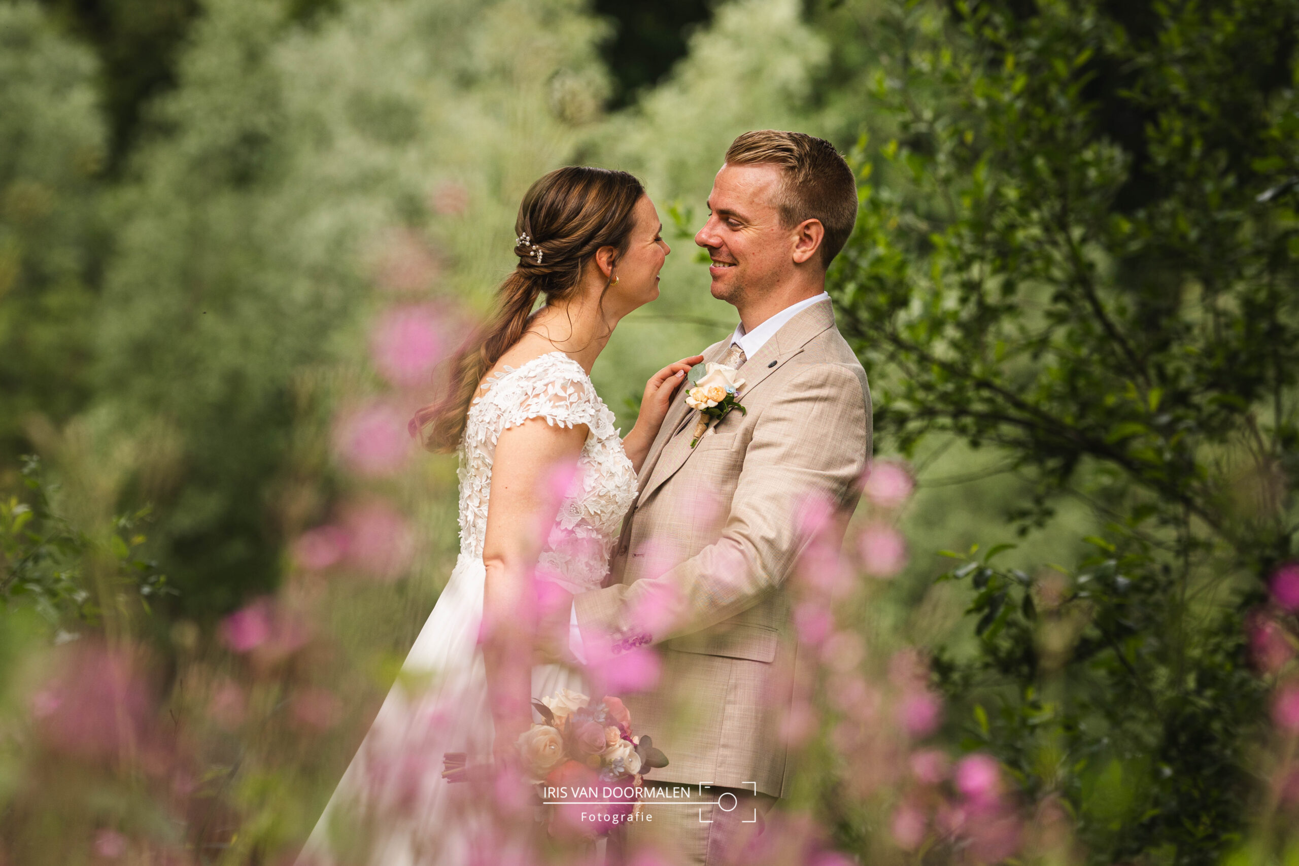 bruid en bruidegom in bos, achter roze bloemen