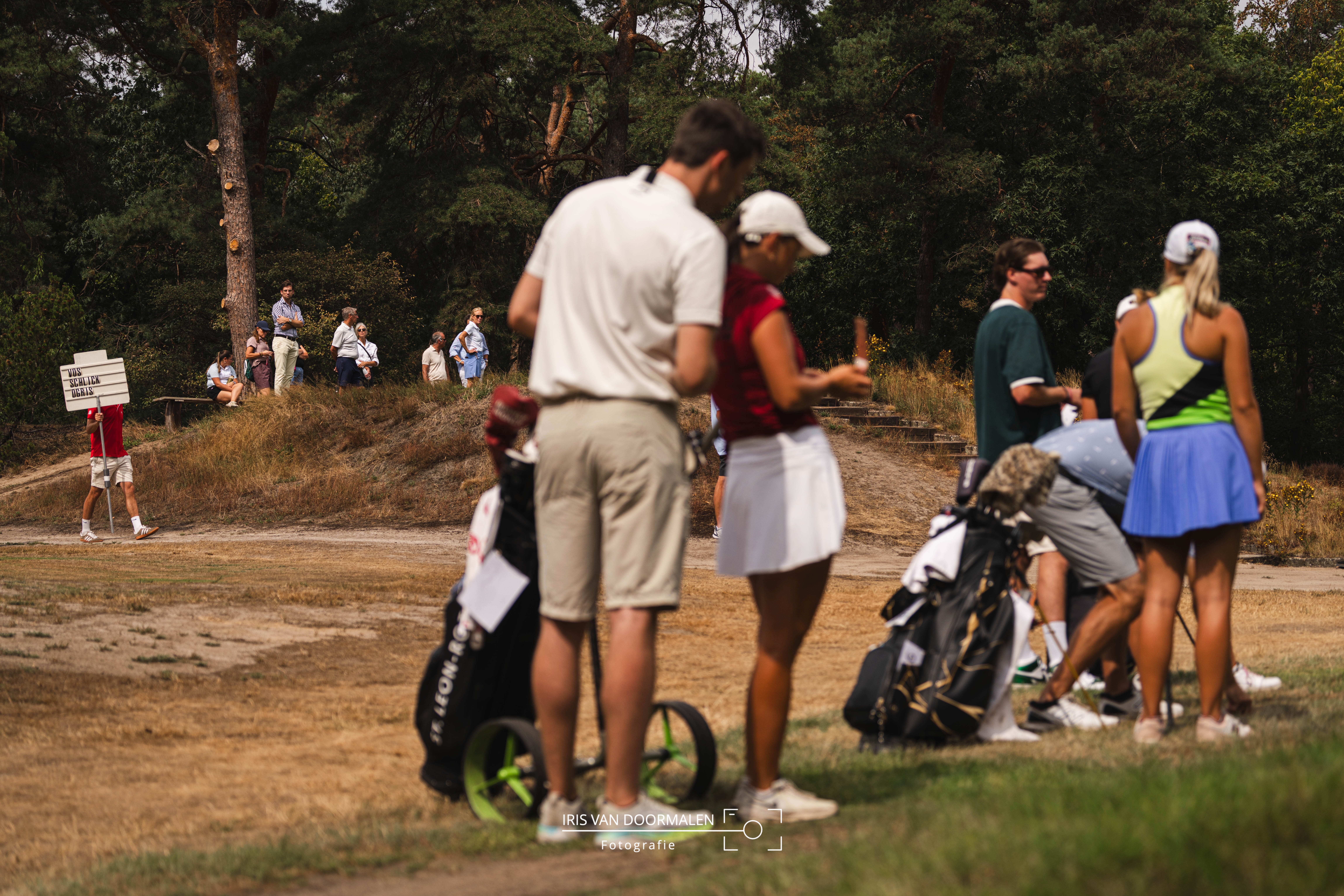 sfeerimpressie golftoernooi, spelers checken afslag, publiek op achtergrond