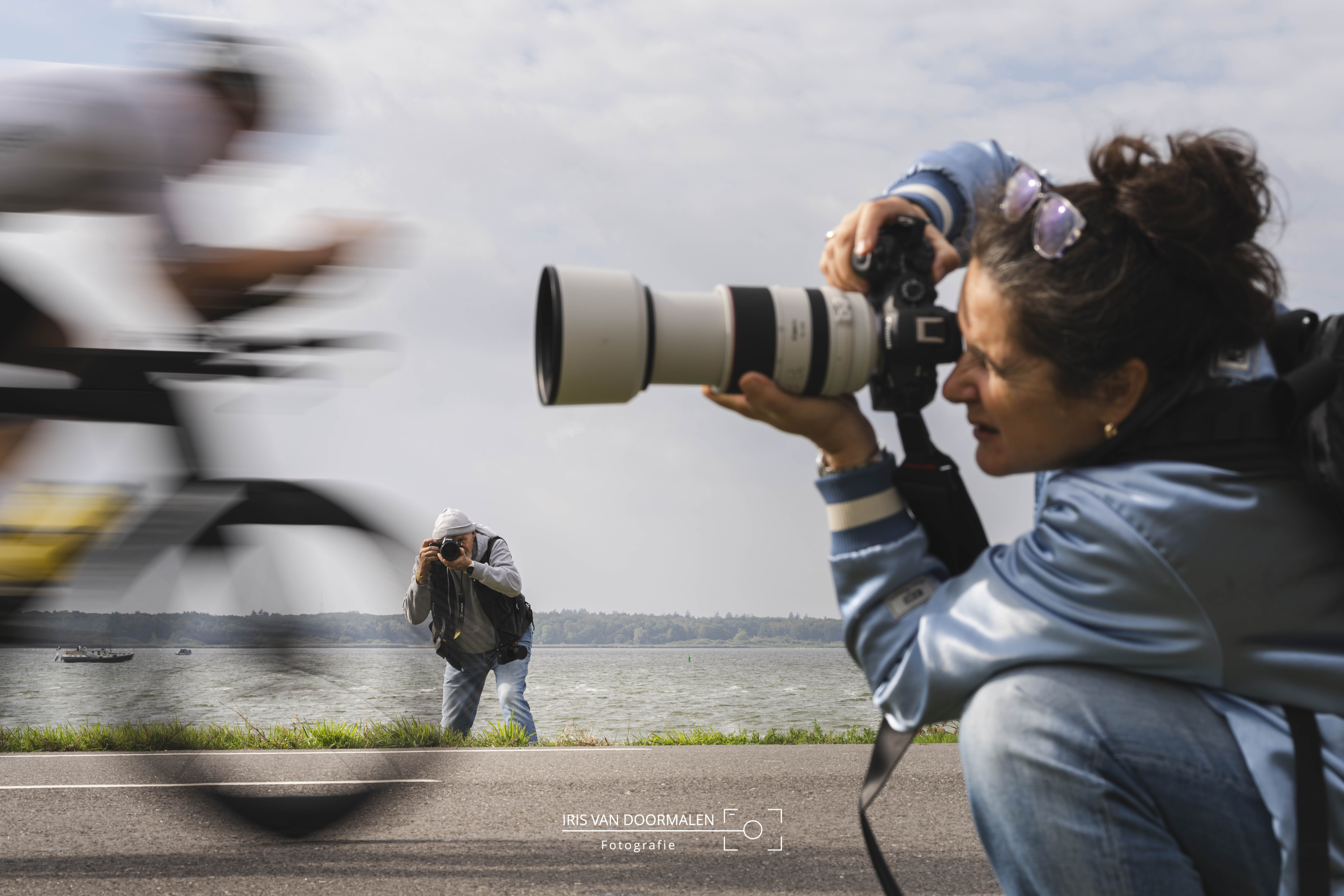 triatlon almere, twee fotografen leggen van andere kant triatleet op de fiets vast die voorbij raast